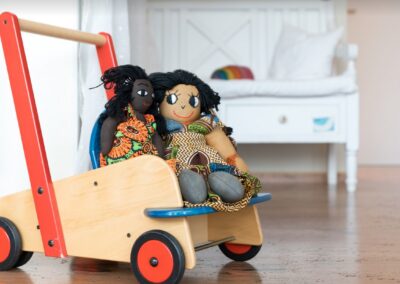 2 Puppen in einem Puppenwagen aus Holz